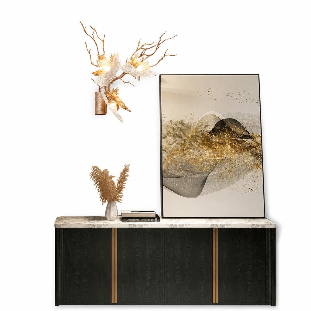 Brass branch sconce with glowing glass blossoms above a black sideboard with marble top