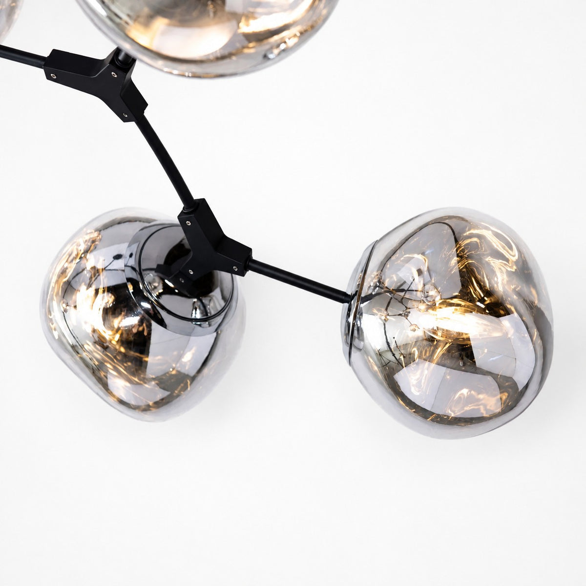 Close-up of matte black arm joints and illuminated reflective acrylic globe shades