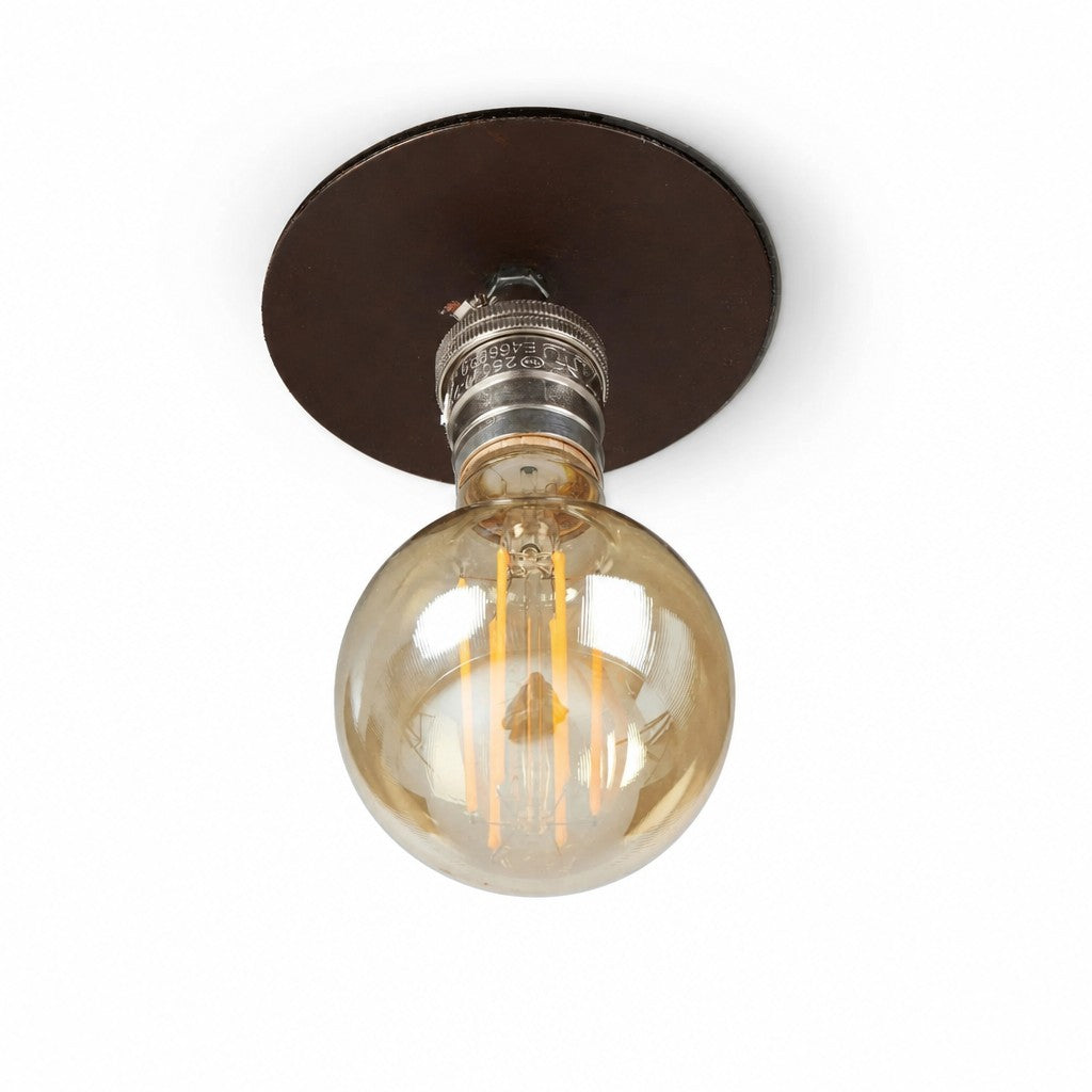 Rust brown ceiling plate with exposed amber globe filament bulb seen from below