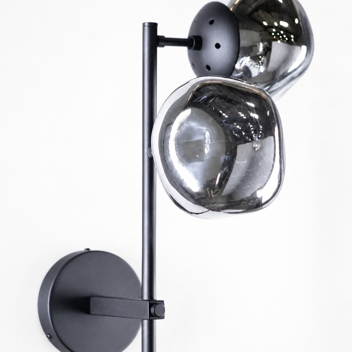 Close detail of two smoked glass globes on black metal rod and round wall plate
