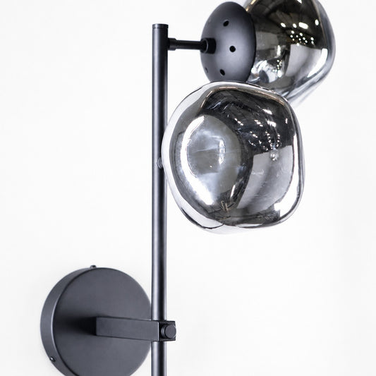 Close detail of two smoked glass globes on black metal rod and round wall plate