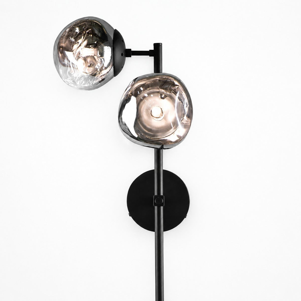 Angled view of black rod sconce holding two molten-shaped amber and grey glass shades