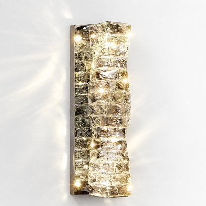 Illuminated sconce glowing warm gold on a white wall, casting starry light patterns