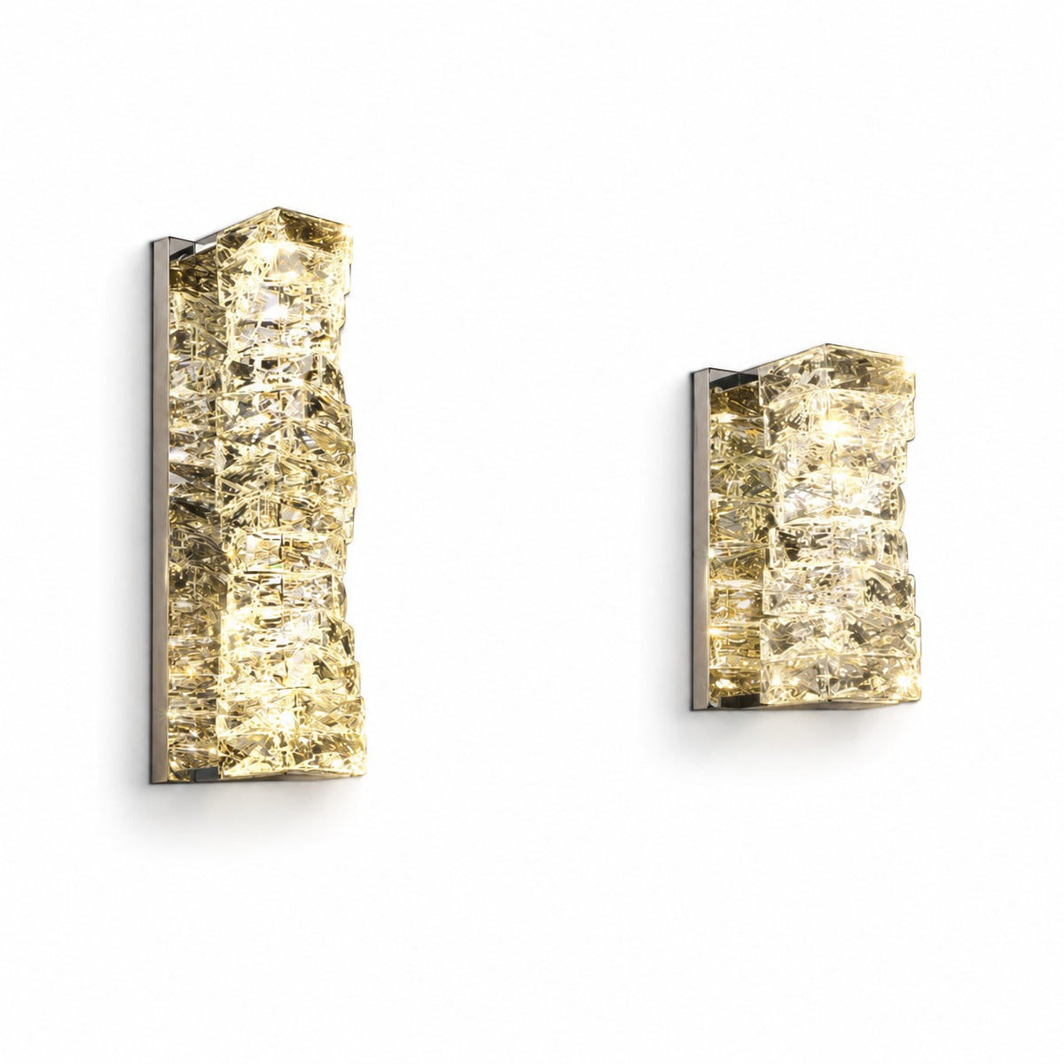 Two lit crystal sconces side by side on white wall, tall and compact sizes