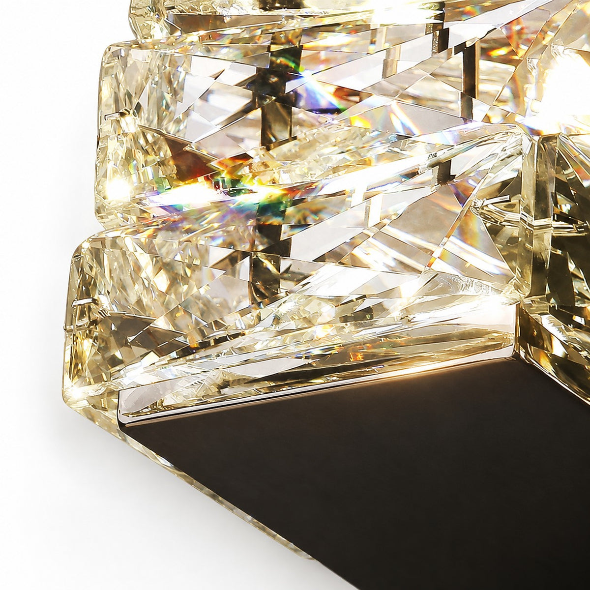 Close-up of stacked faceted crystal blocks throwing rainbow refractions beside dark metal base