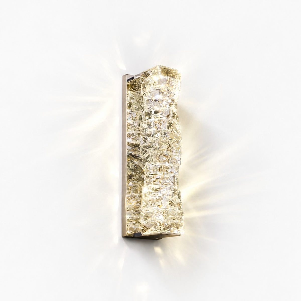 Tall crystal sconce lit on white wall, light rays radiating across the surface