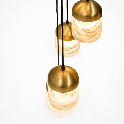 Close-up of three lit pendants, domed brass caps glowing over veined alabaster shades