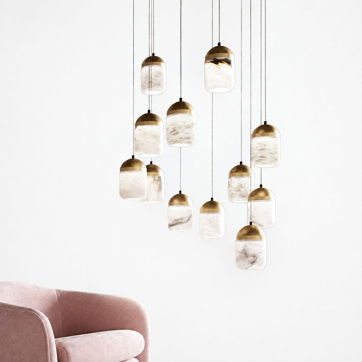 Cascading alabaster and brass pendant cluster in white room above a pink velvet armchair