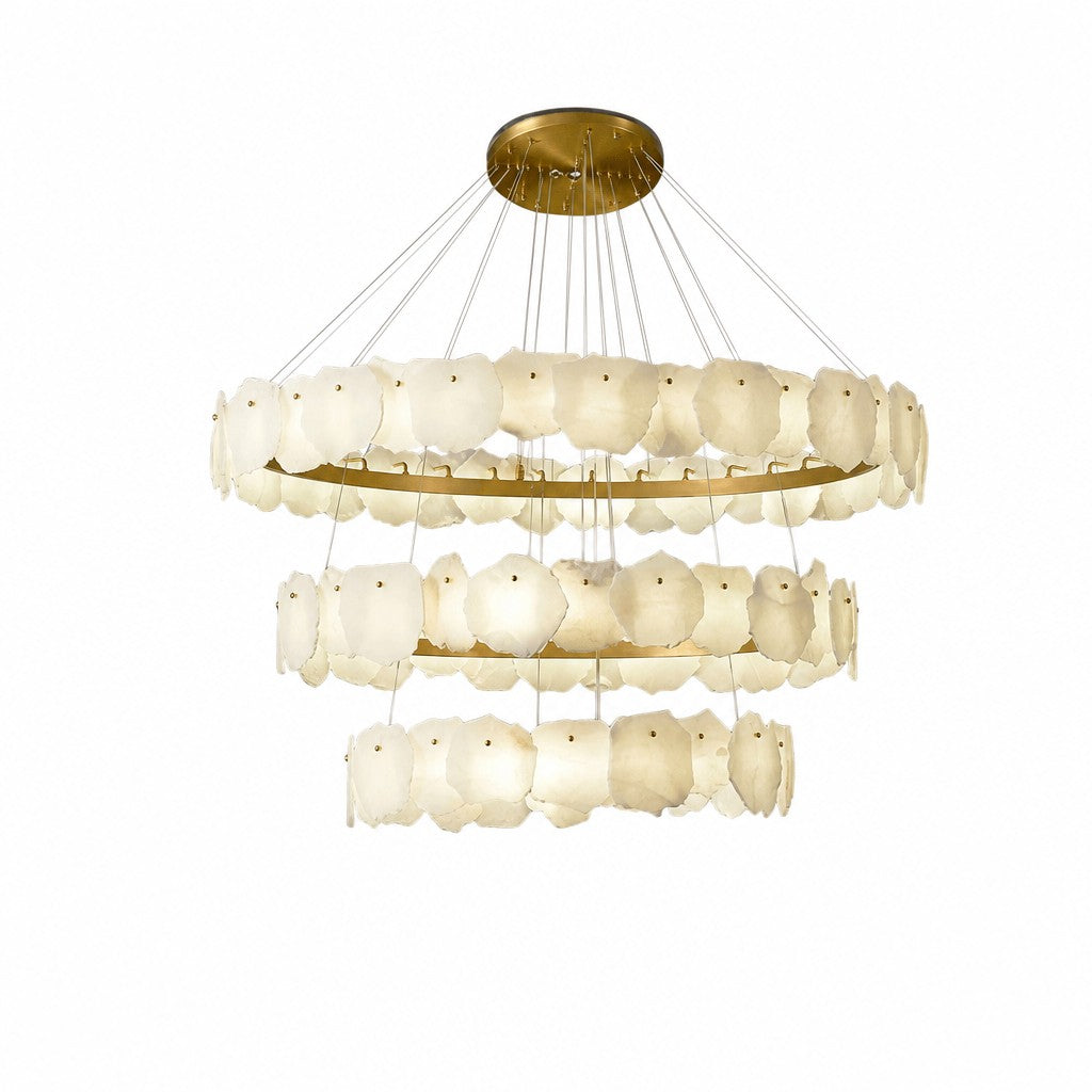 Angled view of three-tier chandelier, warm cream stone tiles glowing against brushed brass frames