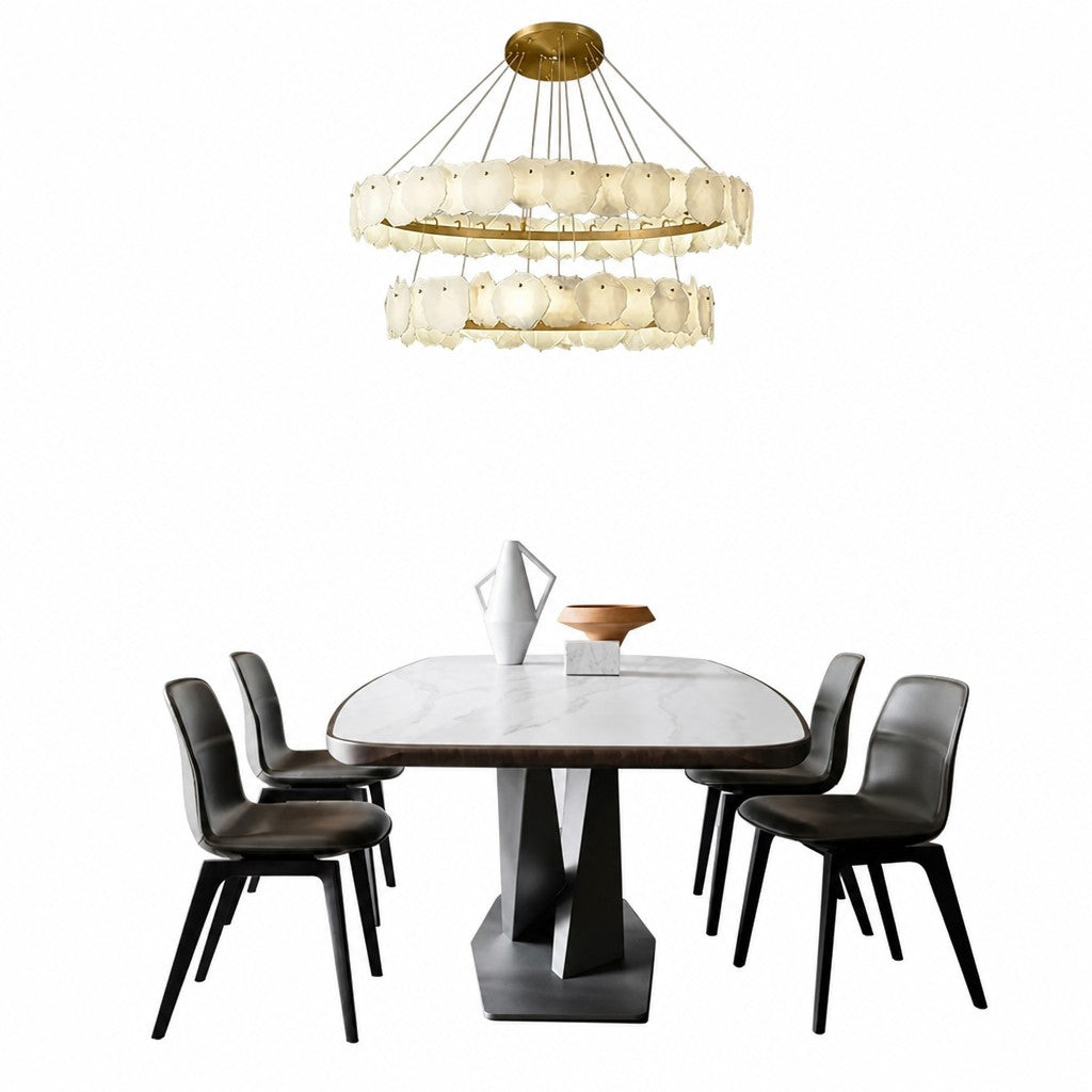 Two-tier chandelier hanging above marble dining table with dark leather chairs and ceramic vase