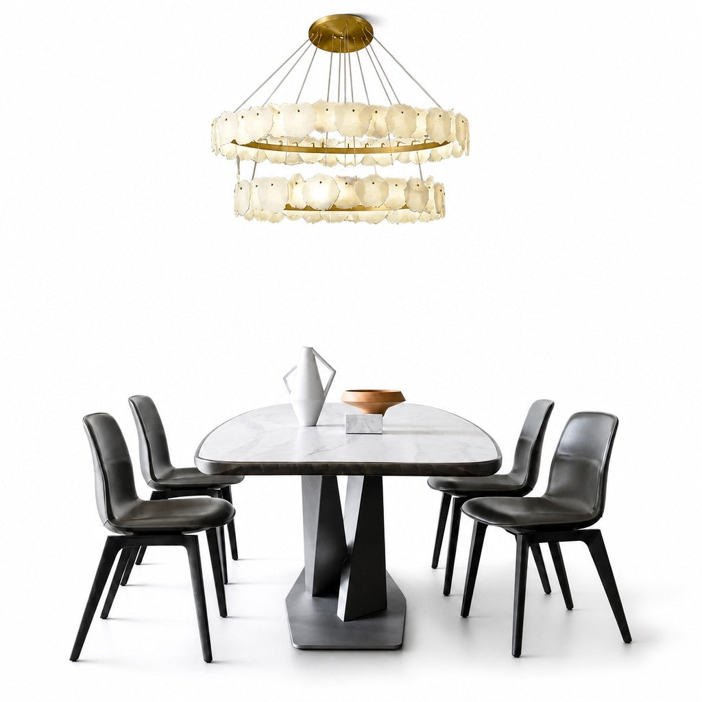 Lit chandelier over white marble dining table, black chairs, copper bowl, bright modern setting