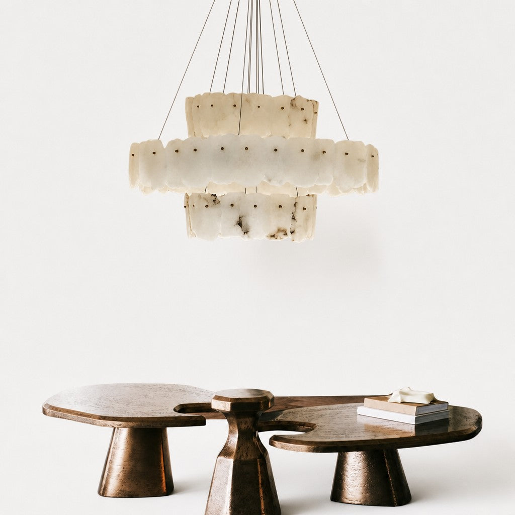 Close interior view of veined alabaster tiers above sculptural bronze coffee tables and stacked books