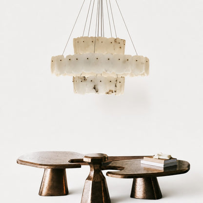 Close interior view of veined alabaster tiers above sculptural bronze coffee tables and stacked books