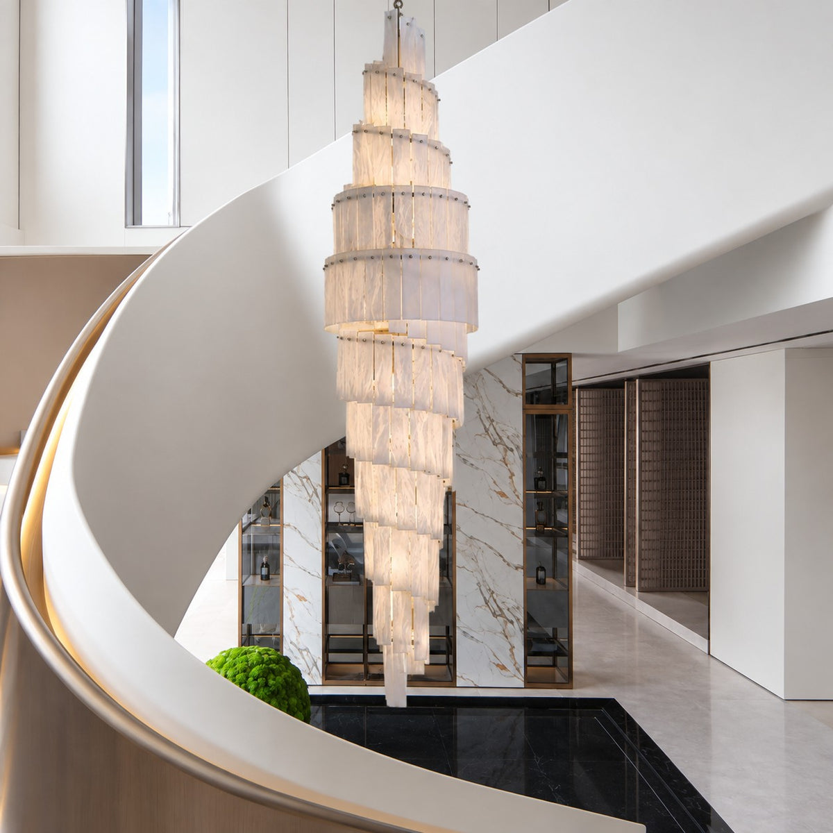 Spiral alabaster chandelier cascading beside a curved white staircase in a bright marble entry hall